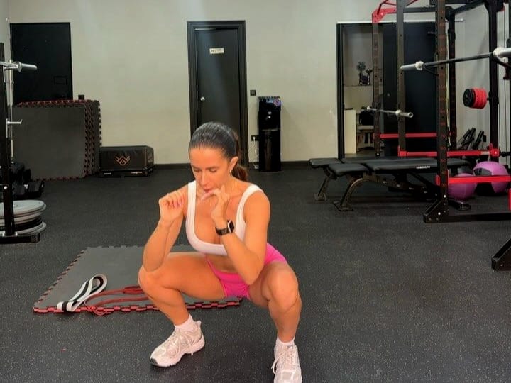 Sandra Llamas haciendo sentadilla con goma en la sala de entrenamiento